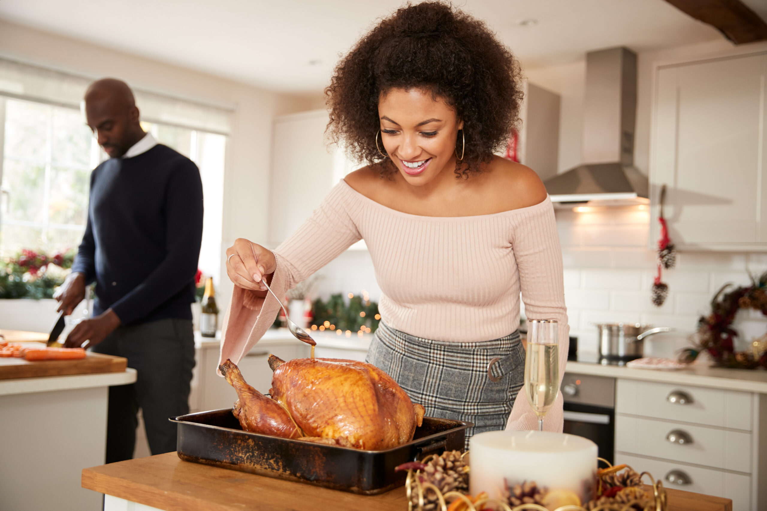 An African American woman seasons a turkey for Thanksgiving dinner