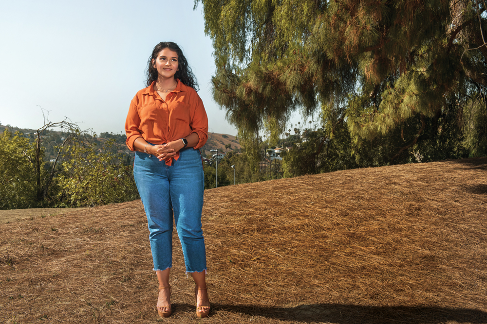 Brianna Villanueva, a bariatric surgery patient, stands on a hill in front of some trees