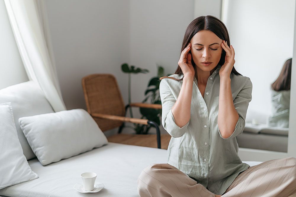 Woman practices meditation, relaxation and stress relief to manage recurrent headaches and migraine.